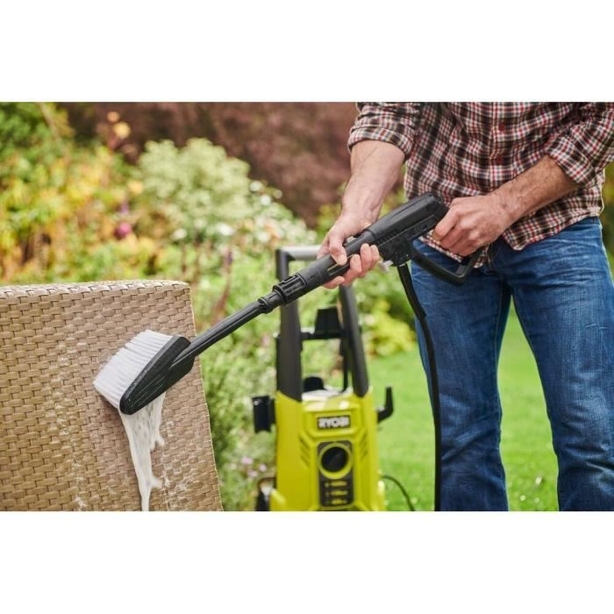 Mann reinigt Gartenmöbel mit Hochdruckreiniger und Bürstenaufsatz.