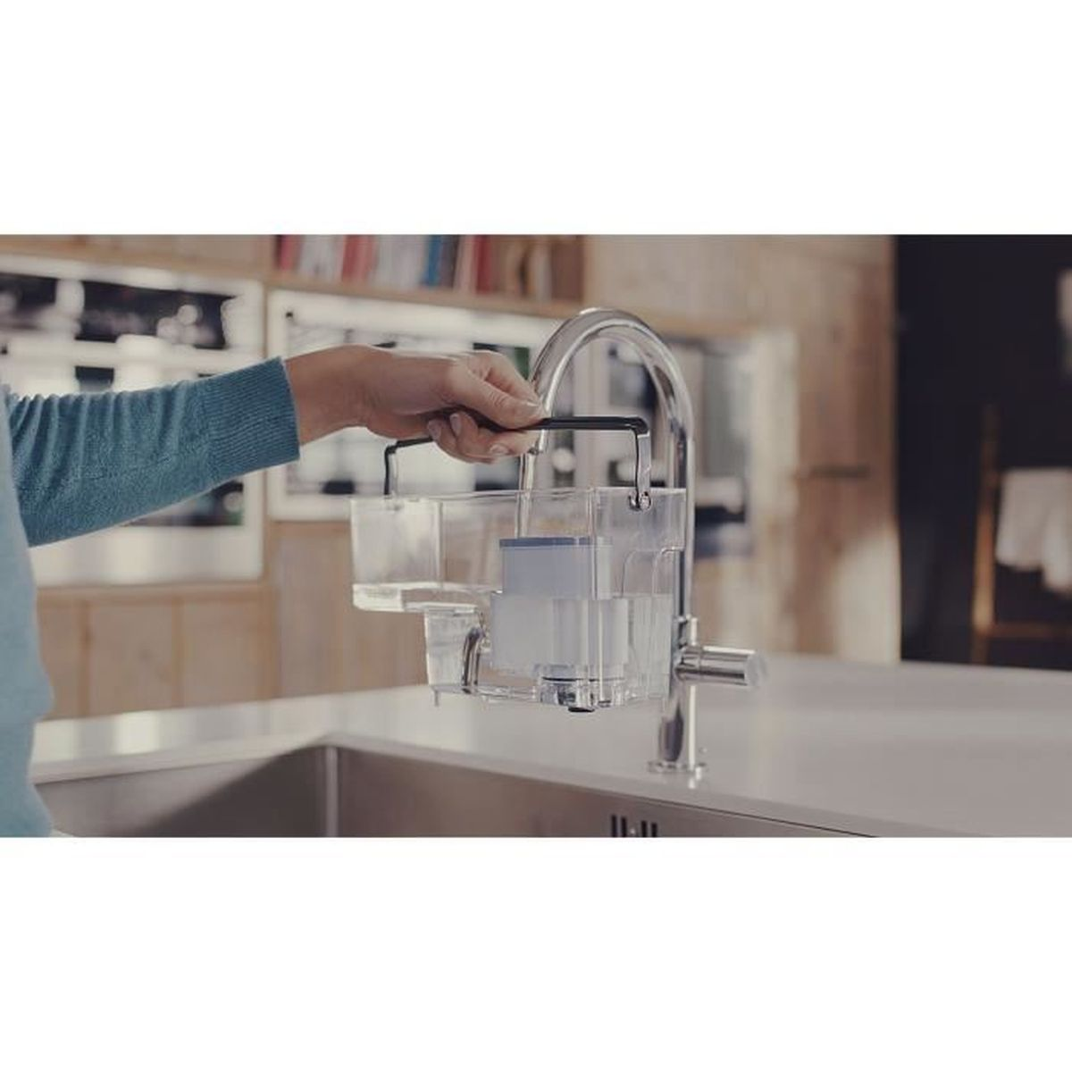 Eine Hand hält einen Wasserfilteraufsatz unter einem Wasserhahn in einer Küchenspüle.