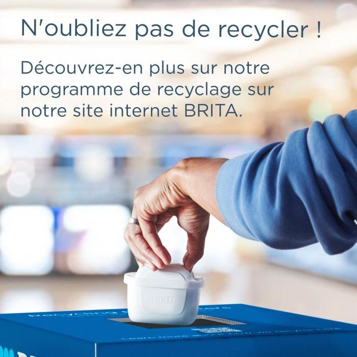 Eine Hand wirft einen Brita-Filter in eine blaue Recyclingbox.