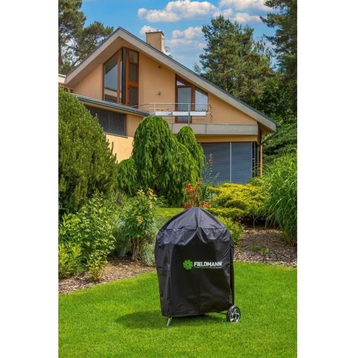 A round grill covered by a black protective tarp stands on a green lawn in front of a house.