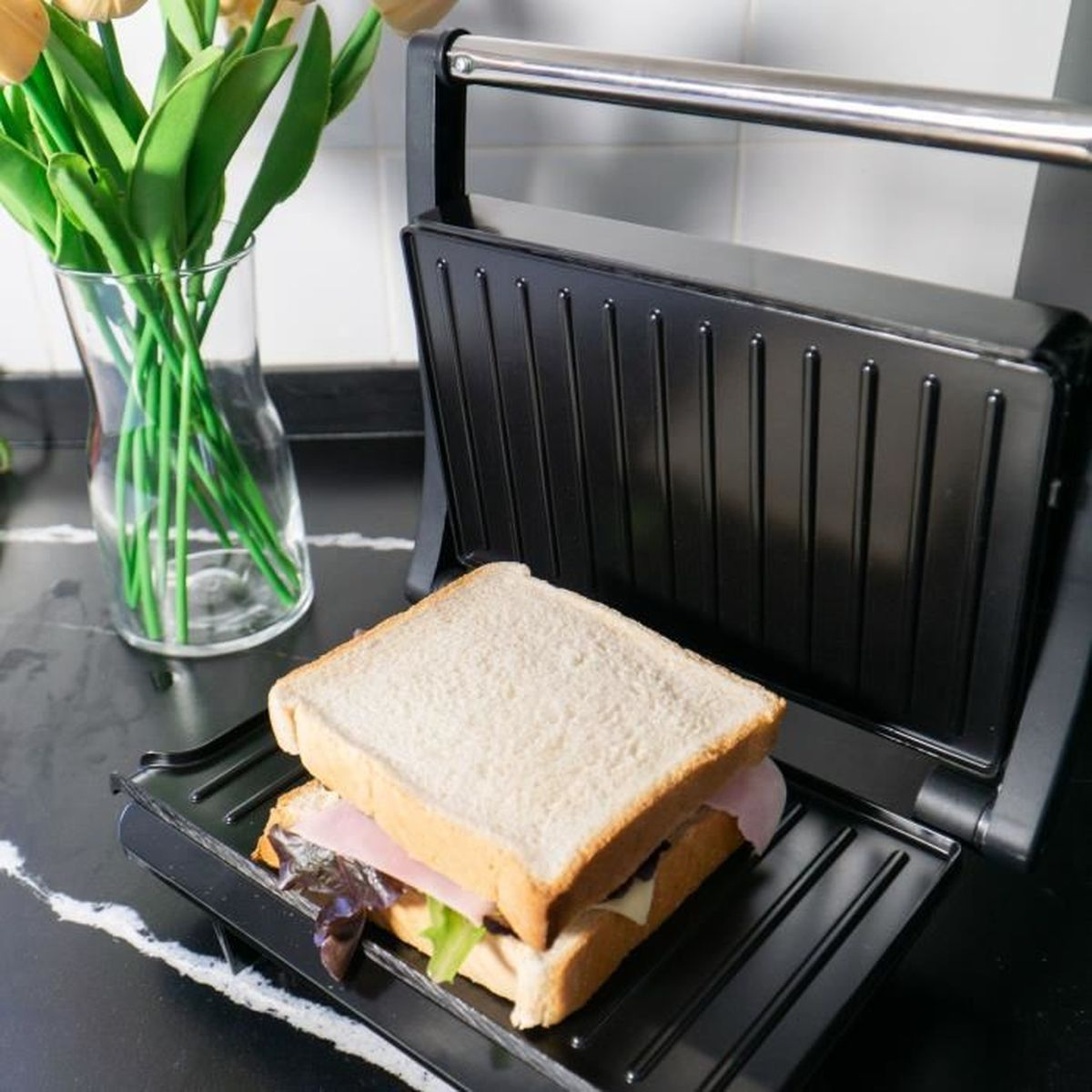 Un sándwich en una parrilla con flores al fondo.