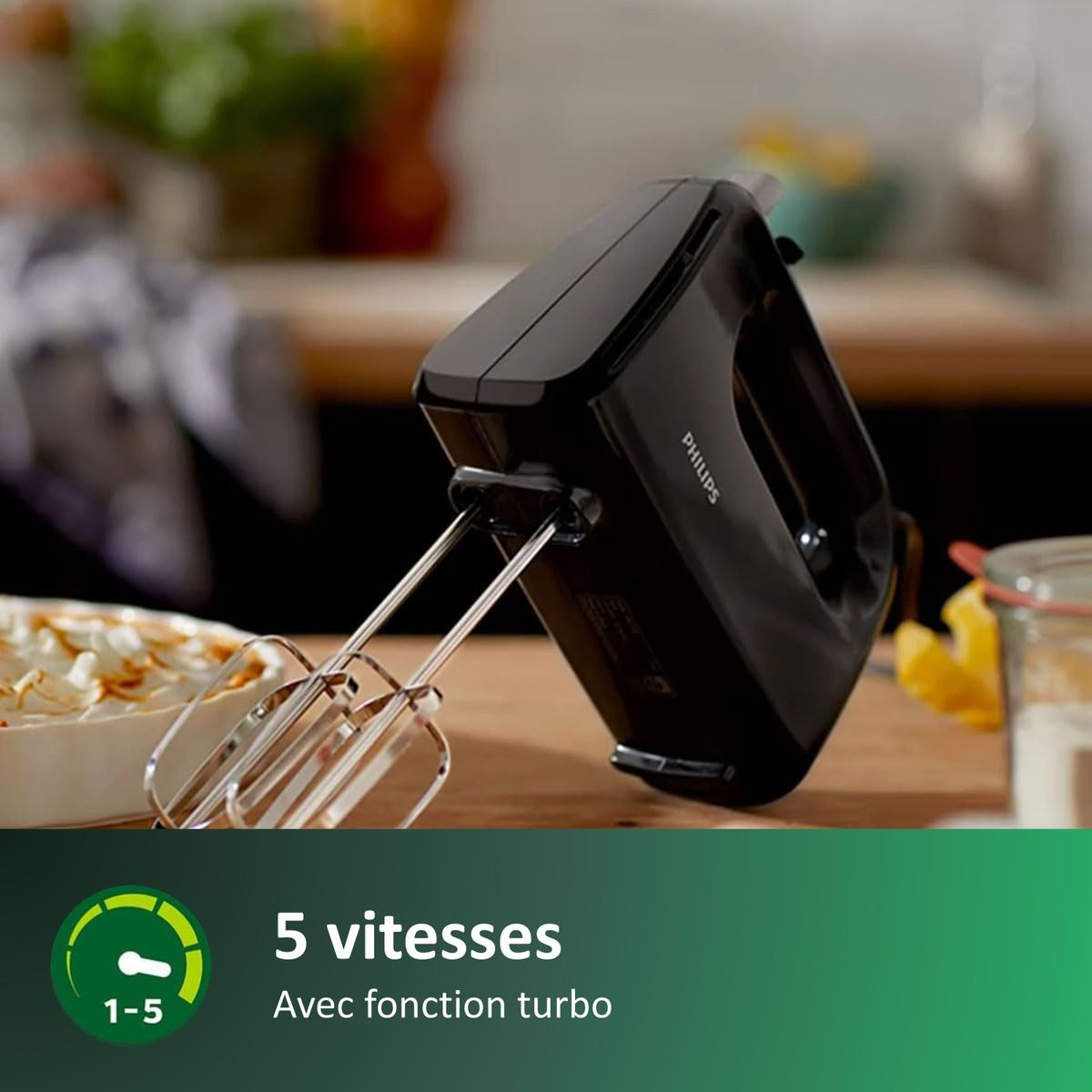 Zwarte Philips handmixer met gardes naast een dessert.