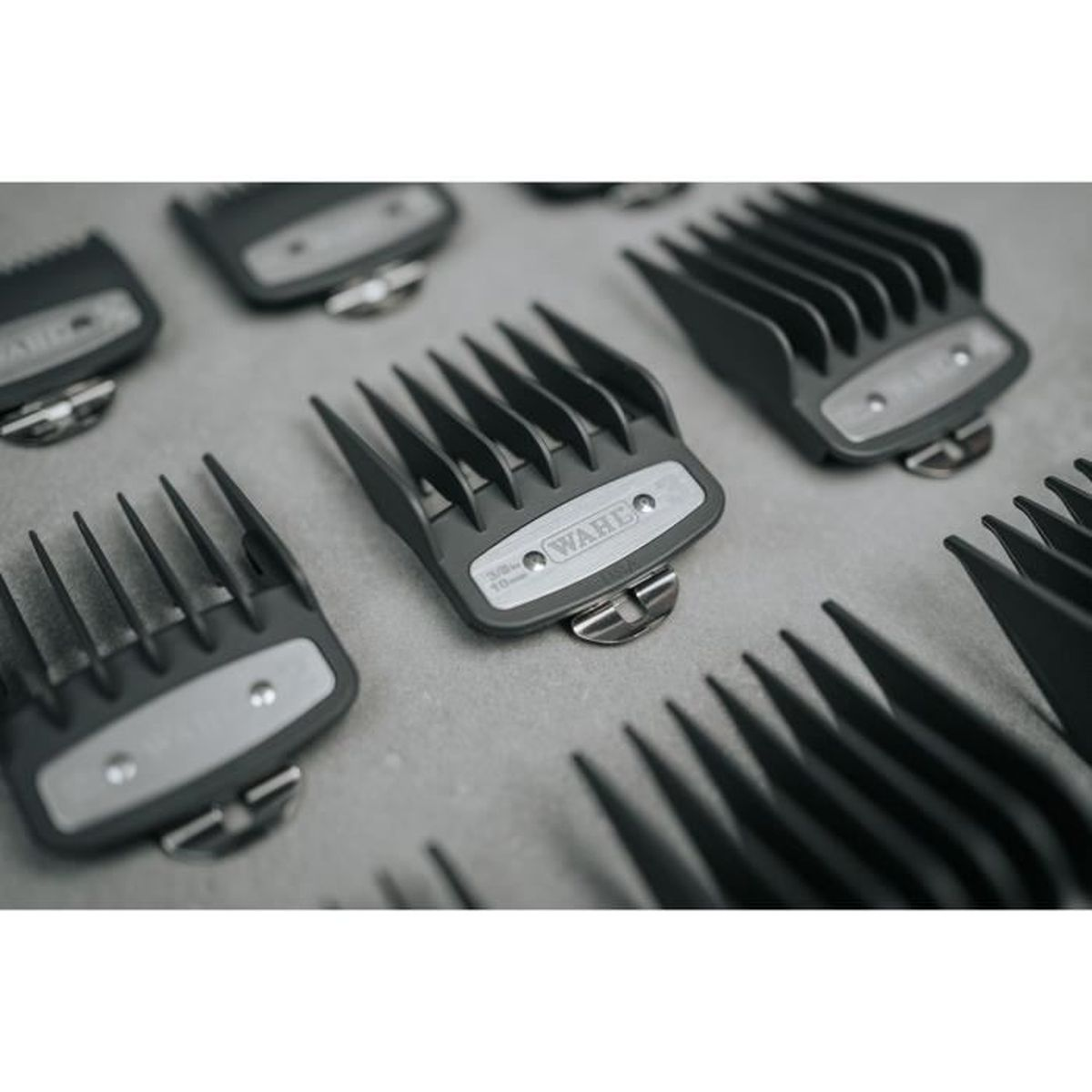 Kilka szarych nasadek do maszynki do strzyżenia włosów leży na szarej powierzchni.