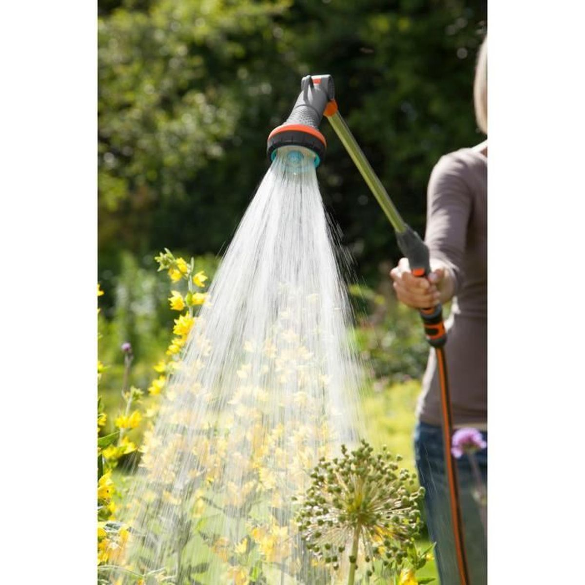 Una persona annaura fiori gialli in un giardino con un tubo.