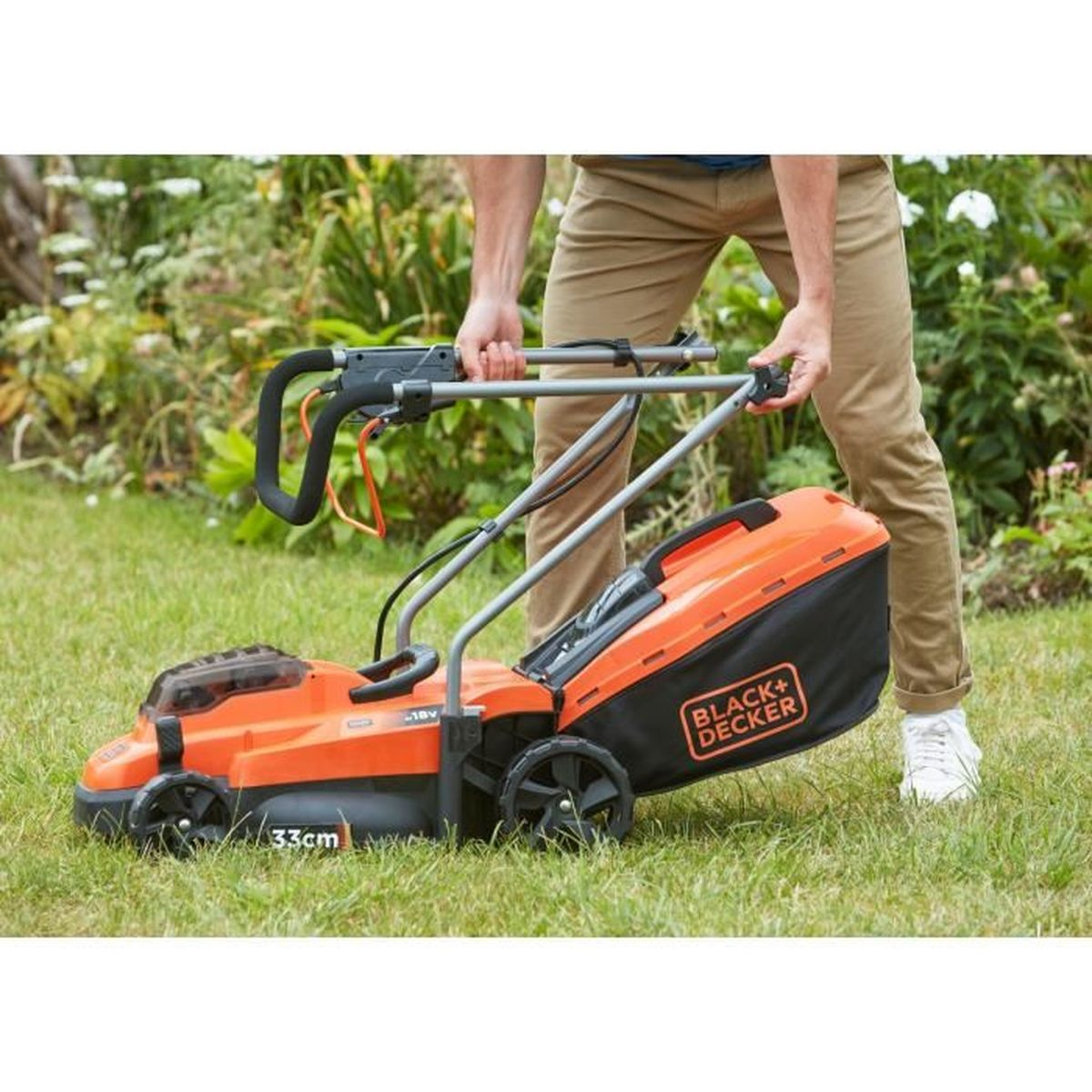 Ein Mann schiebt einen orangefarbenen Rasenmäher mit schwarzem Fangkorb im Garten.