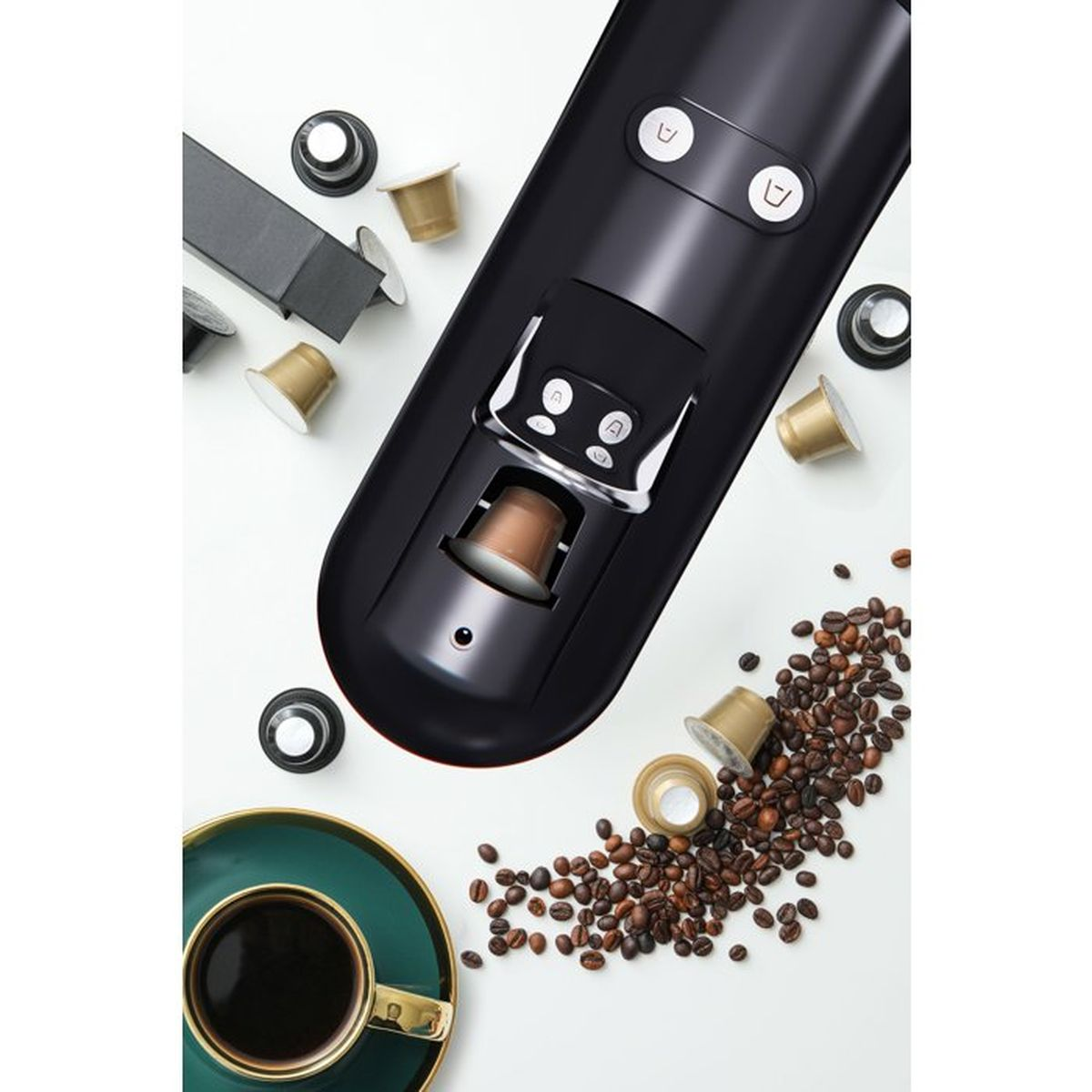 Macchina da caffè nera con cialde, chicchi di caffè e una tazza.
