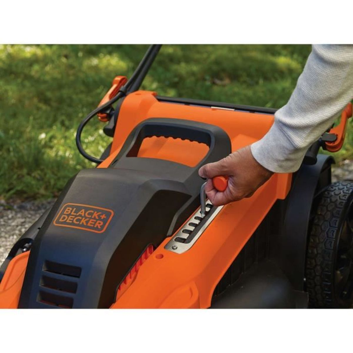 Eine Hand stellt einen orangefarbenen Hebel an einem schwarzen und orangefarbenen Rasenmäher ein.