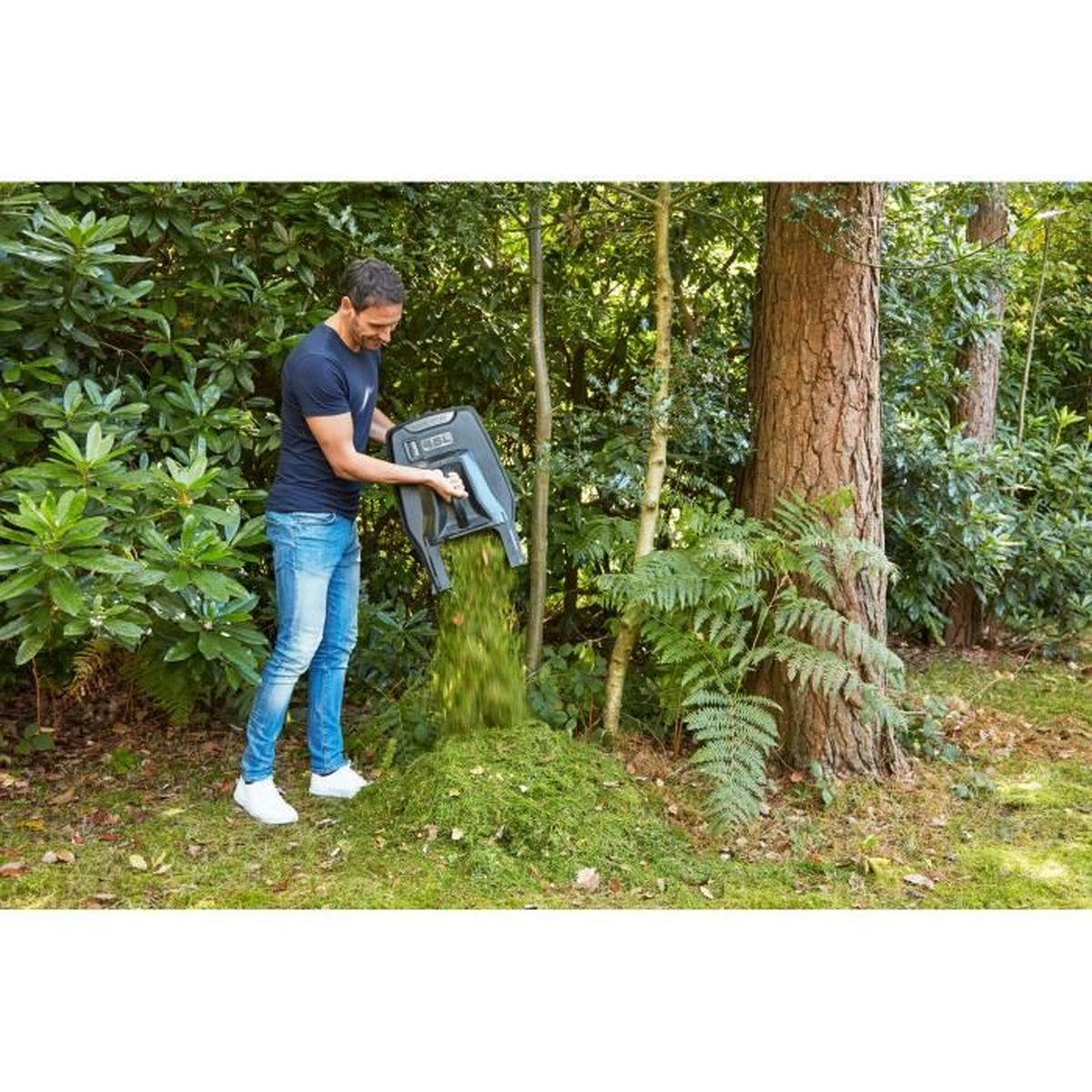 Hombre vacía recortes de césped de un contenedor en un montón en el bosque.