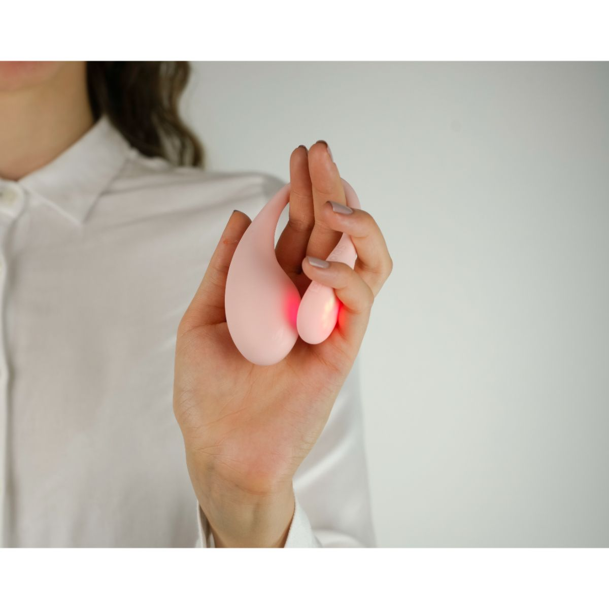 Eine Hand hält ein rosa Objekt mit roten Lichtern.