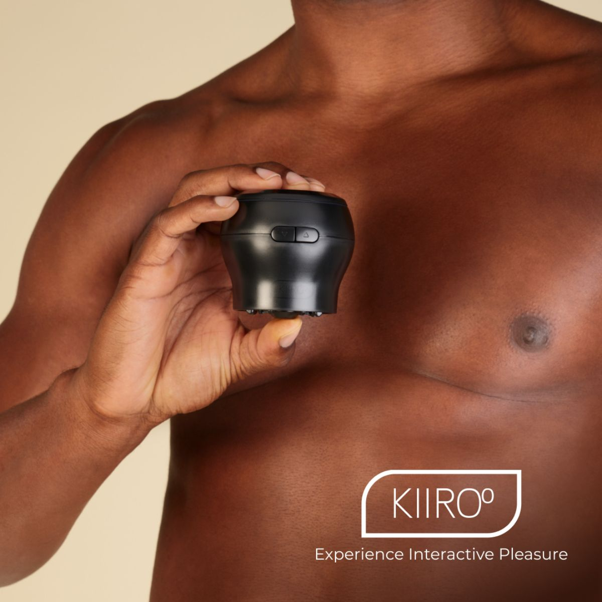 Un hombre sostiene un dispositivo KIIROO negro con botones y una base circular.