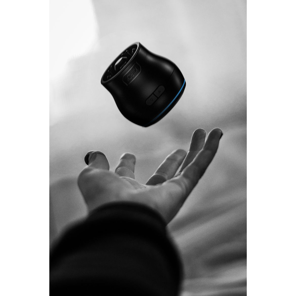 Un altavoz negro flota sobre una mano extendida contra un cielo nublado.
