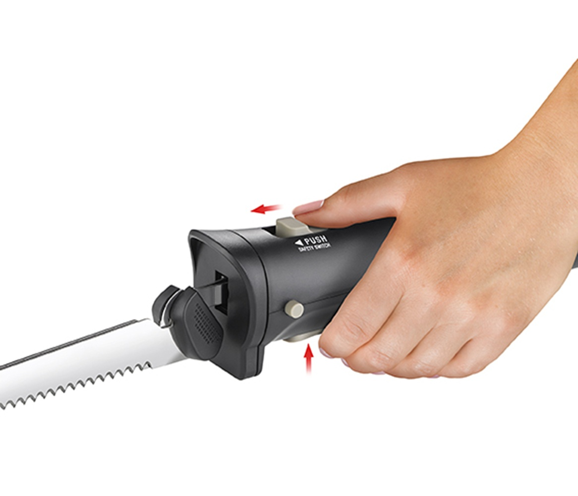 Dłoń naciska wyłącznik bezpieczeństwa w nożu elektrycznym.