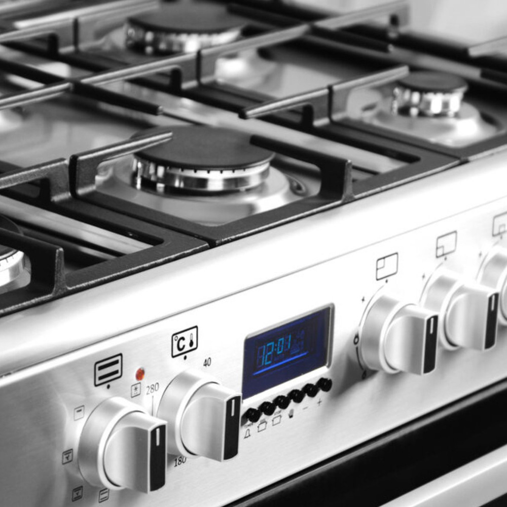 Een zilveren gasfornuis met branders, knoppen en een digitaal display.