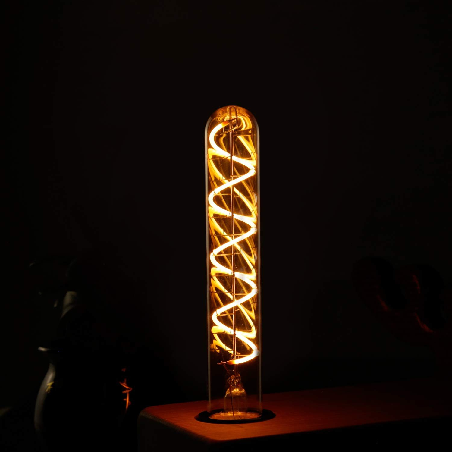 Una lampadina luminosa con filamento a spirale, su sfondo scuro.