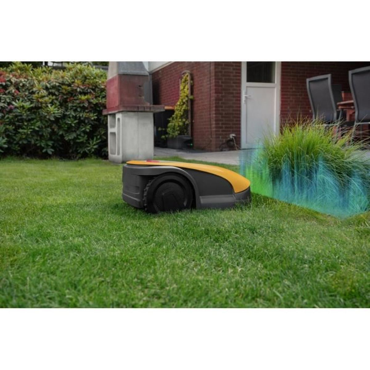 Un robot cortacésped amarillo y negro está sobre un césped verde junto a un arbusto.