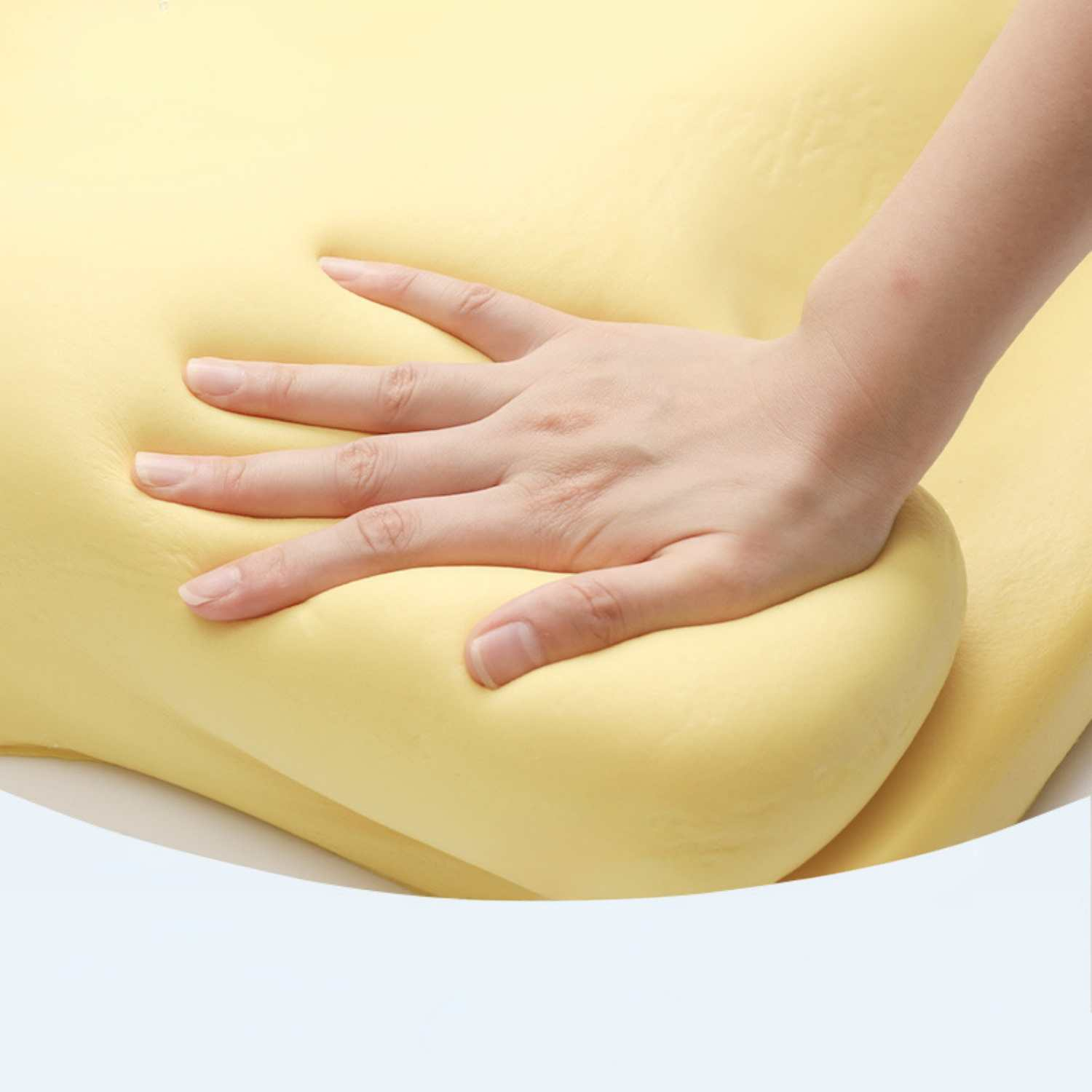 Eine Hand drückt in ein hellgelbes, weiches Material.