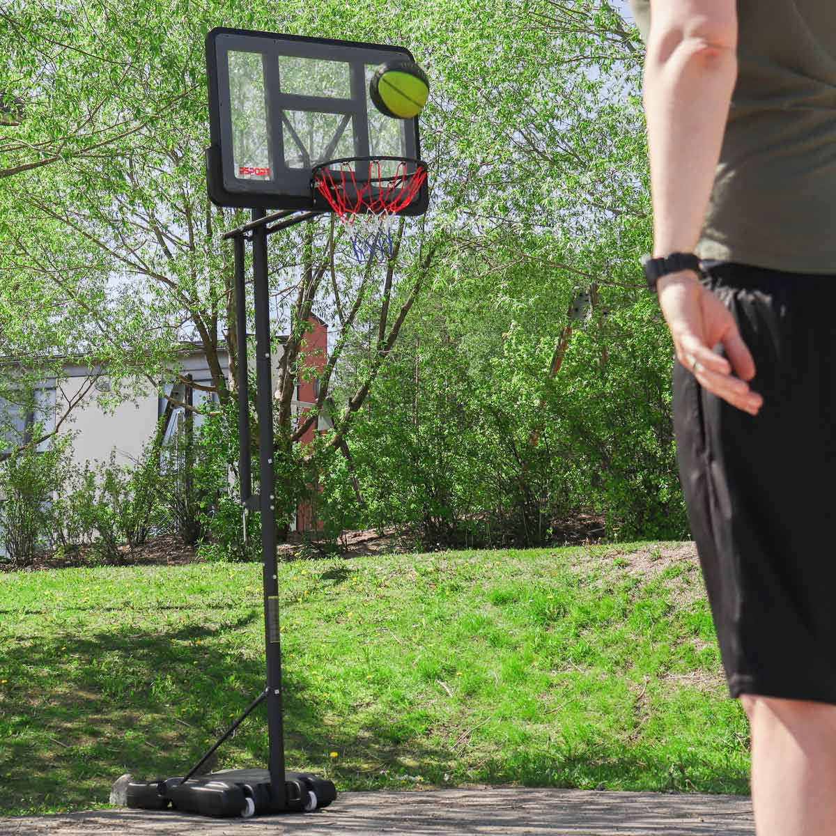 Ein Basketball fliegt auf einen Korb zu, eine Person steht im Vordergrund.