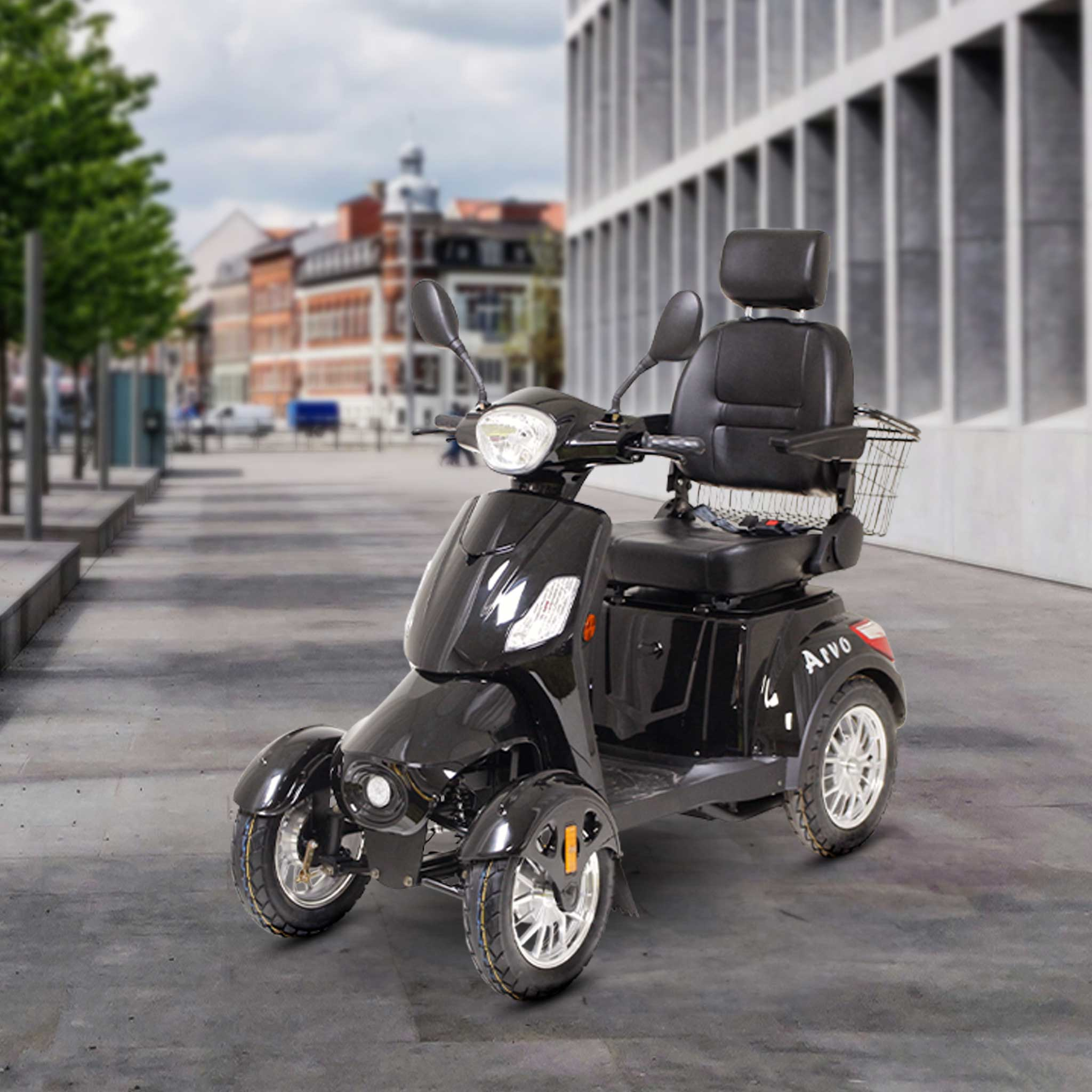 Czarny czterokołowy skuter inwalidzki zaparkowany na chodniku przed budynkami.