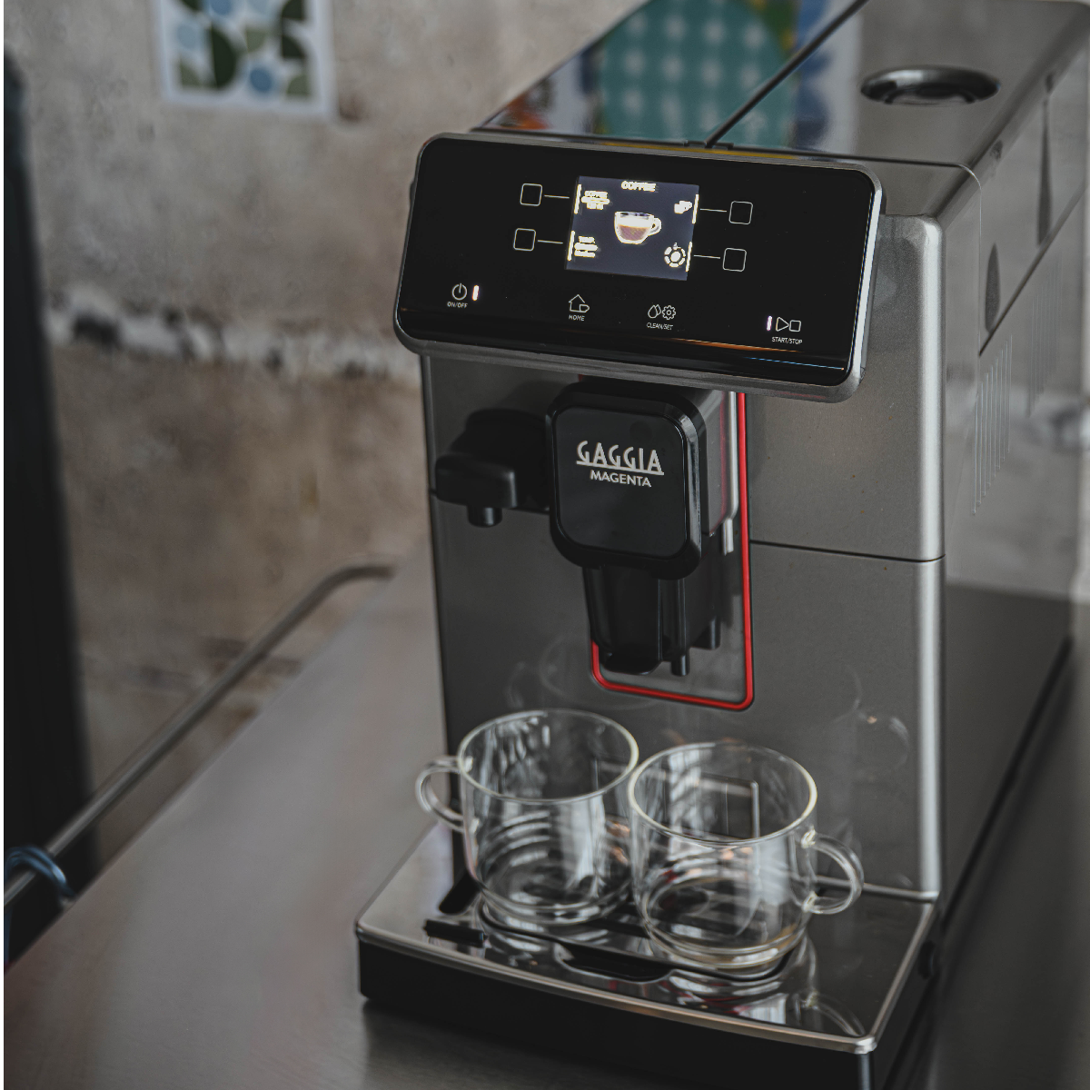 Una moderna macchina da caffè con touchscreen e due bicchieri.