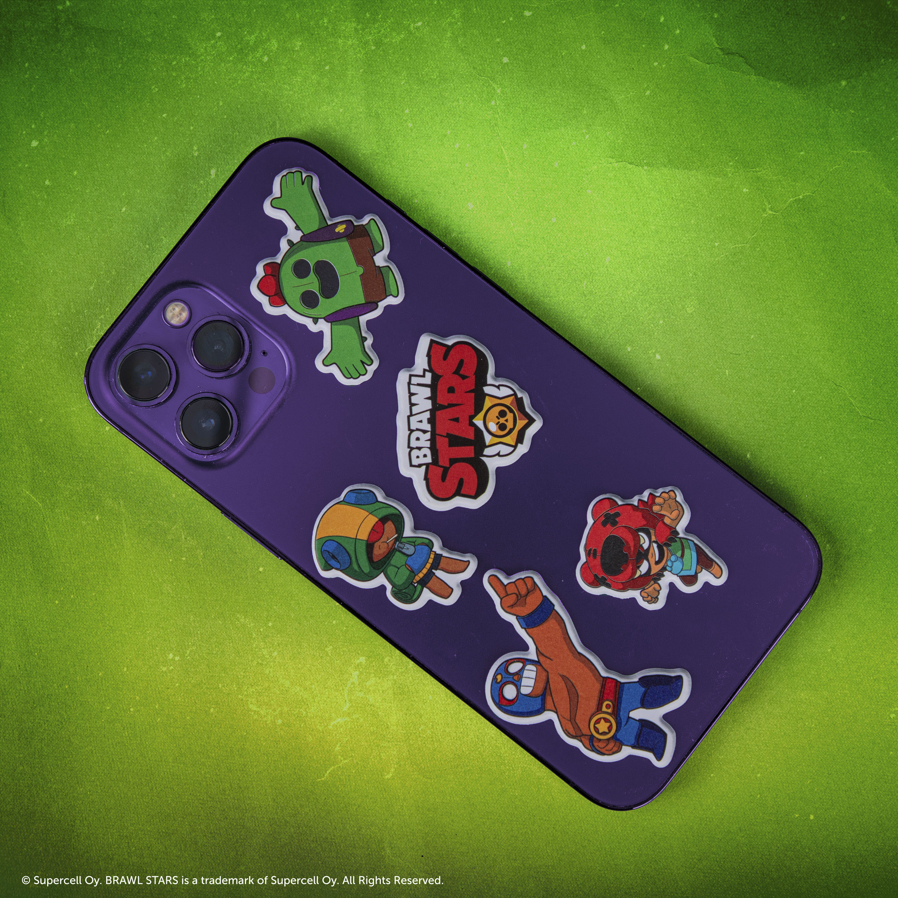 Ein violettes Smartphone mit Brawl Stars-Aufklebern auf grünem Hintergrund.