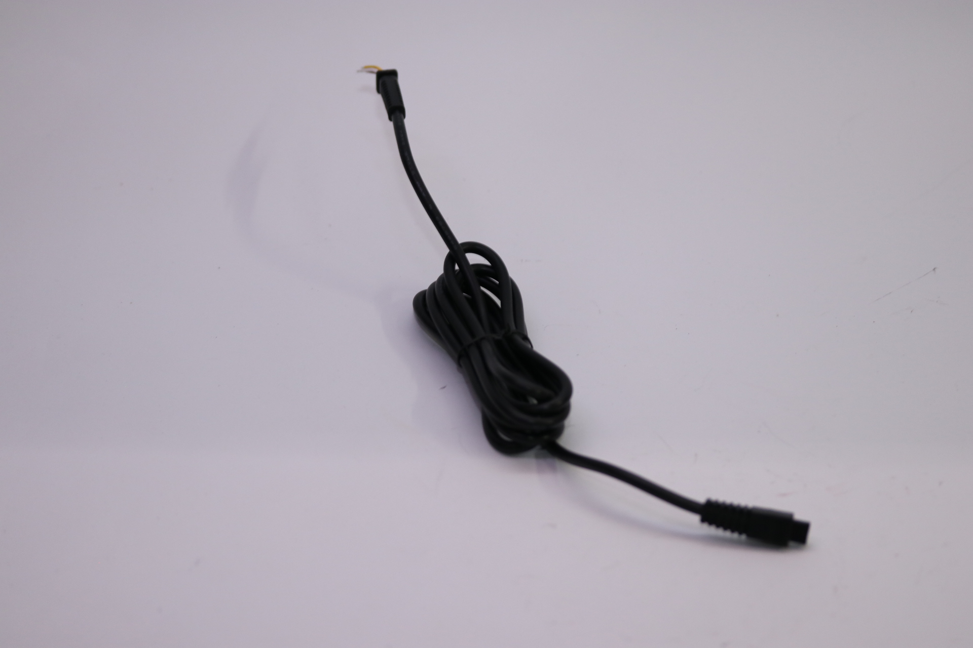 Ein schwarzes Kabel mit zwei Anschlüssen, auf weißem Hintergrund.