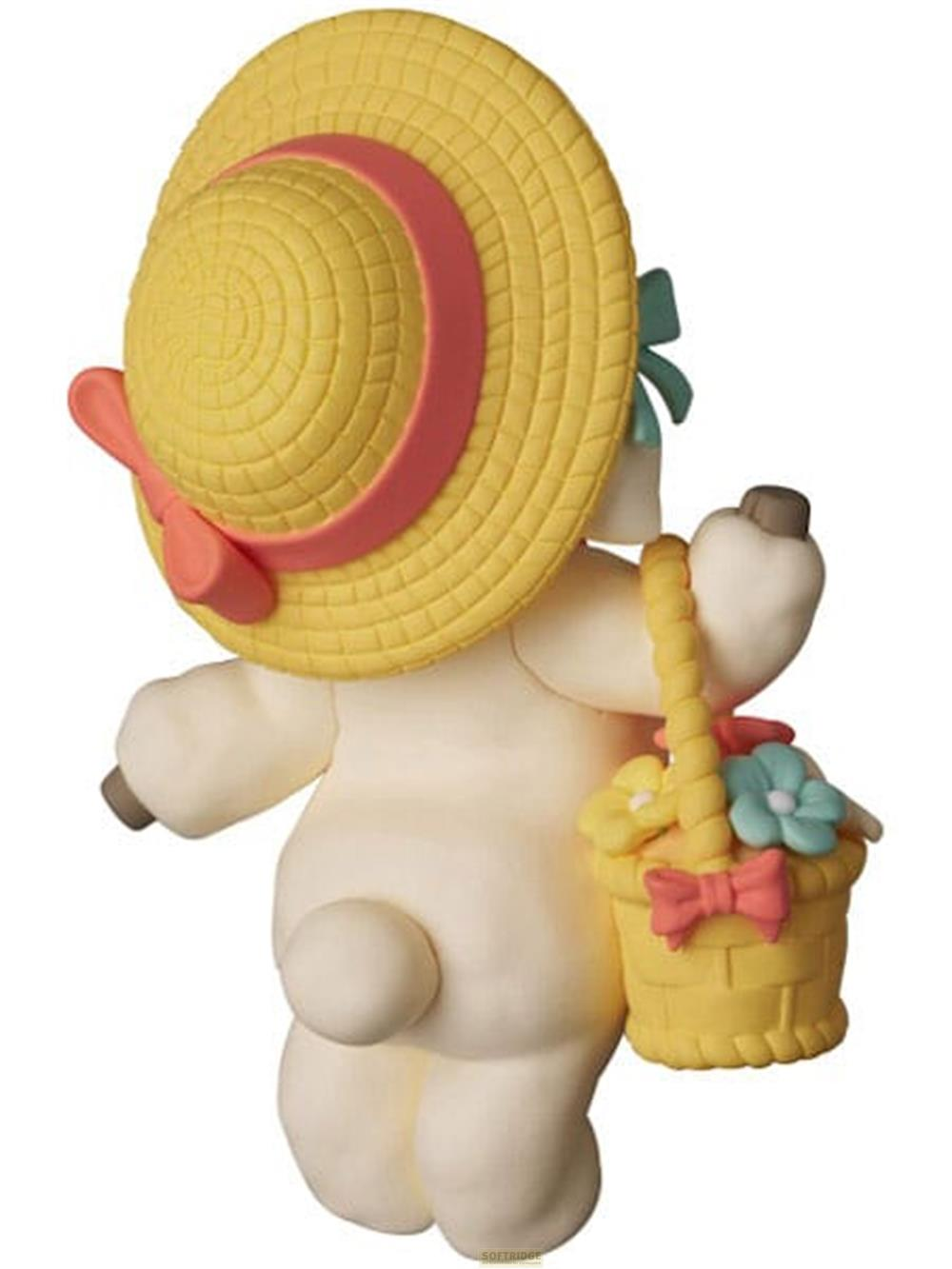 Eine weiße Figur trägt einen gelben Hut und einen Korb mit Blumen und Schleifen.