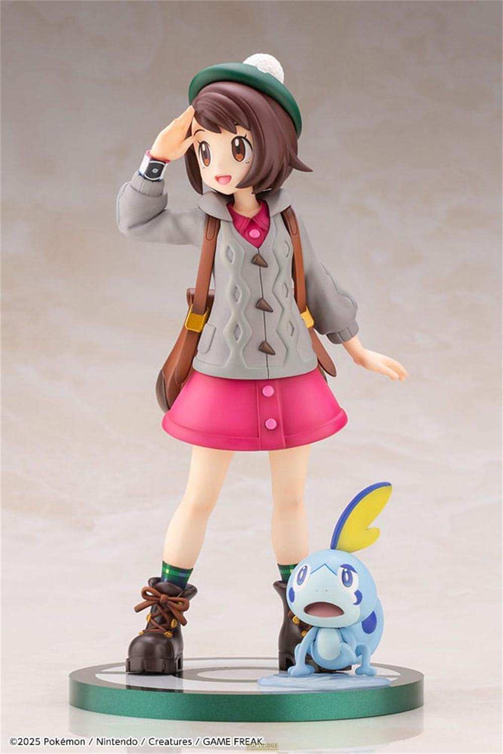 Una figura di ragazza con un Pokémon blu sta su una base verde.