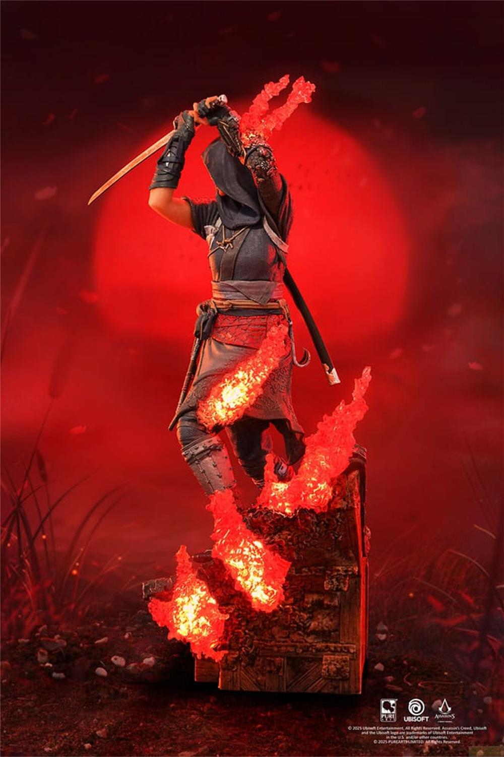 Eine Figur mit Kapuze und Schwert, umgeben von roter Flamme und auf einer Kiste stehend.
