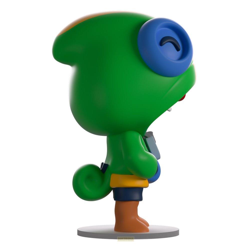 Grüne Figur mit blauen Augen und gelbem Gürtel steht auf grauem Sockel.