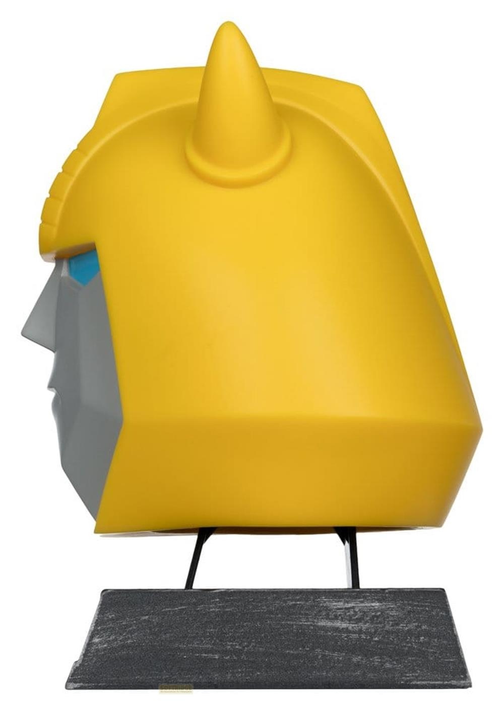 Elmo giallo Transformer con piastra frontale grigia e occhi blu, su piedistallo.