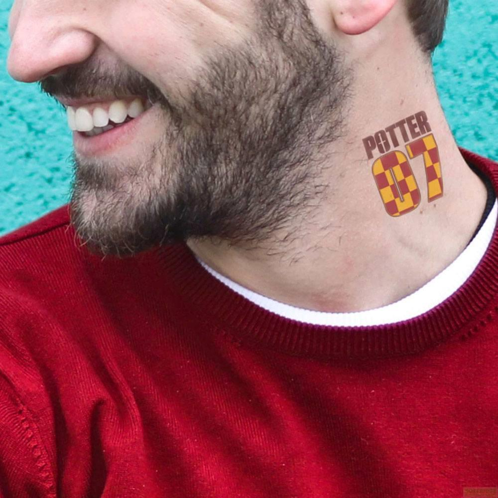 Un homme barbu porte un sweat-shirt rouge avec un tatouage '07' sur le cou.
