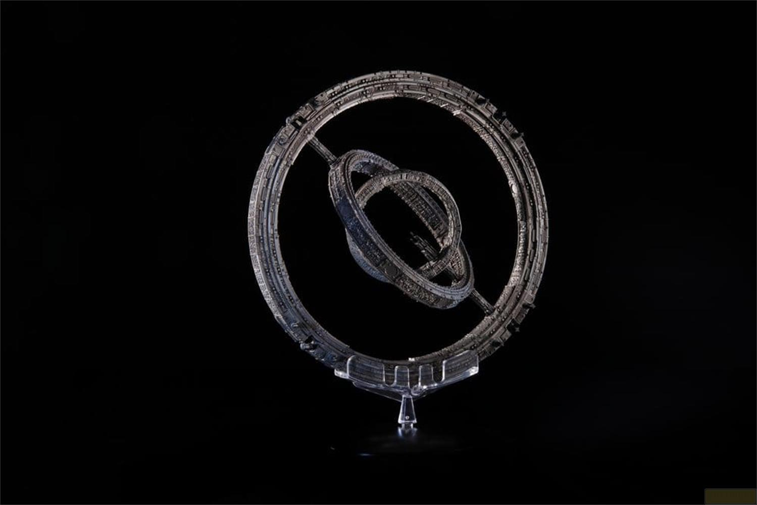 Ein silbernes, ringförmiges Raumschiffmodell mit inneren Ringen auf einem transparenten Ständer.