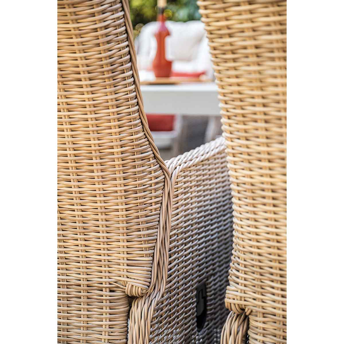 Gros plan de chaises en rotin montrant une table avec une bouteille et des coussins à l'arrière.