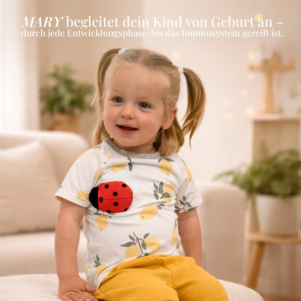 Ein kleines Mädchen mit Zöpfen trägt ein T-Shirt mit Zitronenmuster und Marienkäfer-Applikation.
