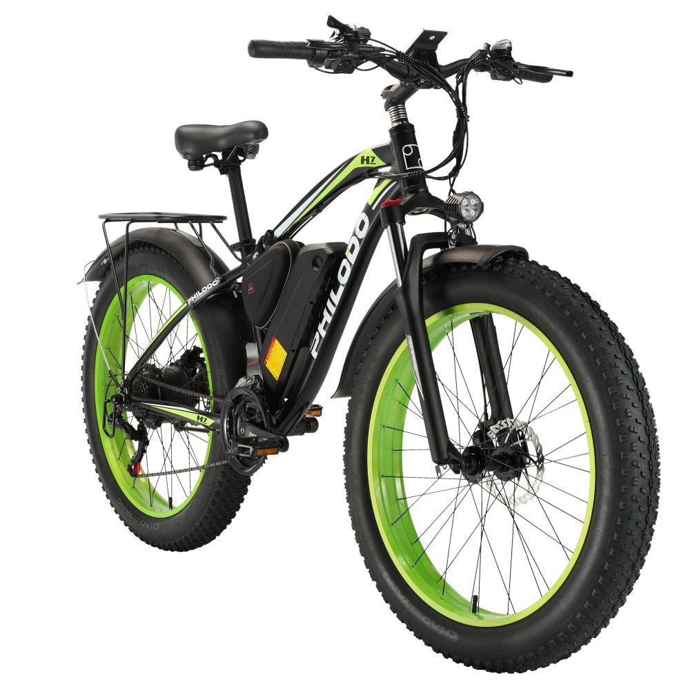 Bicicleta eléctrica negra de llantas anchas con aros verdes y portaequipajes.