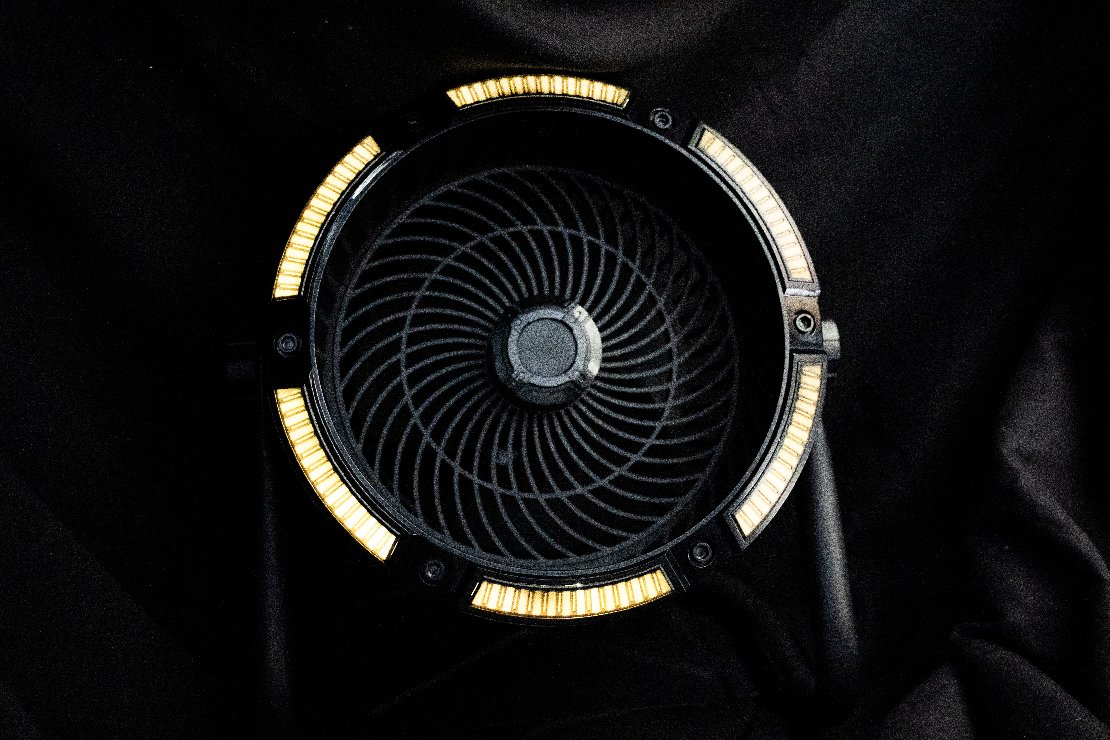 Ein schwarzer Ventilator mit gelben Lichtern auf schwarzem Hintergrund.