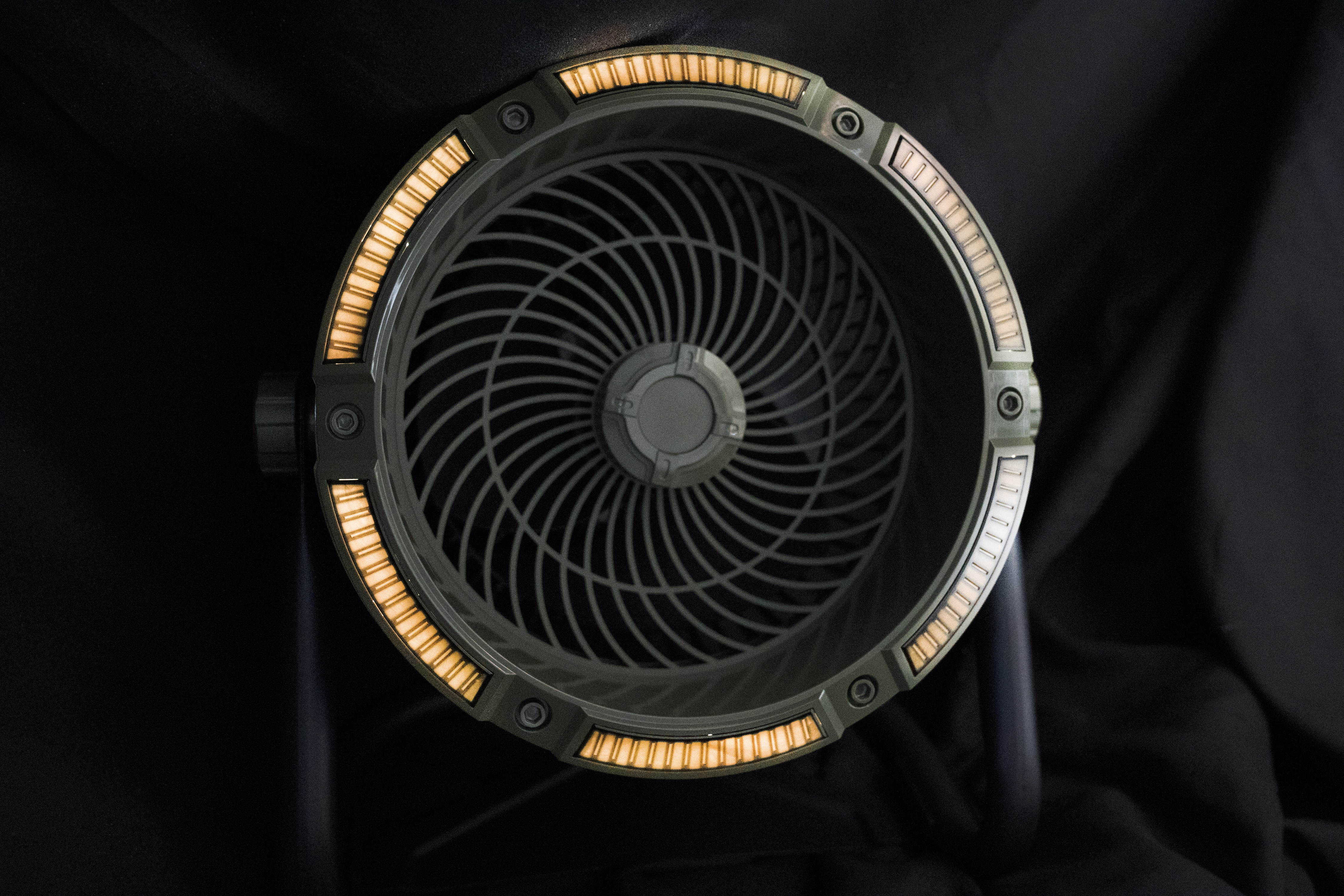 Okrągły, ciemnozielony wentylator z podświetlanym brzegiem, na czarnym tle.
