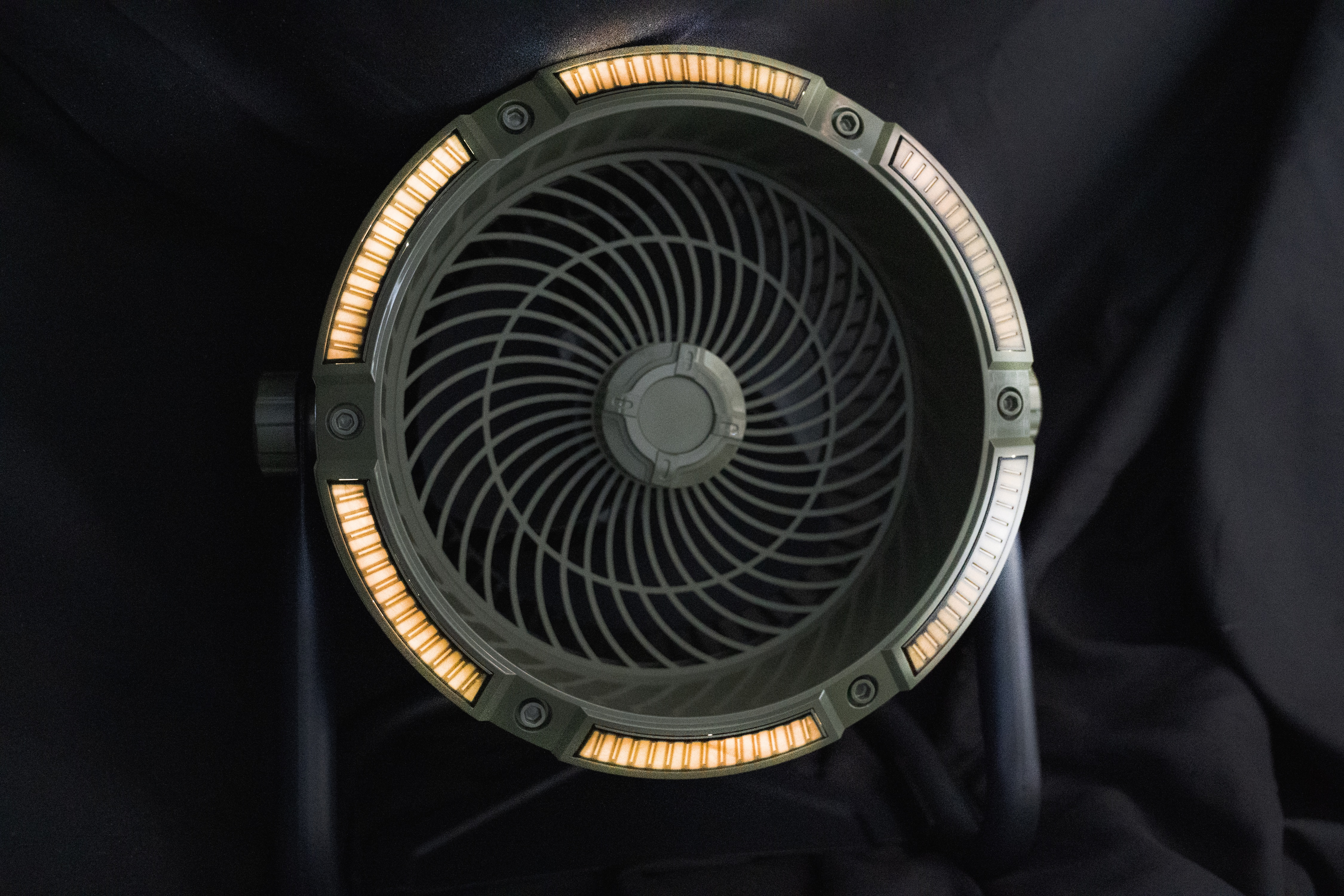 Okrągły, ciemnozielony wentylator z podświetlaną obręczą na czarnym tle.