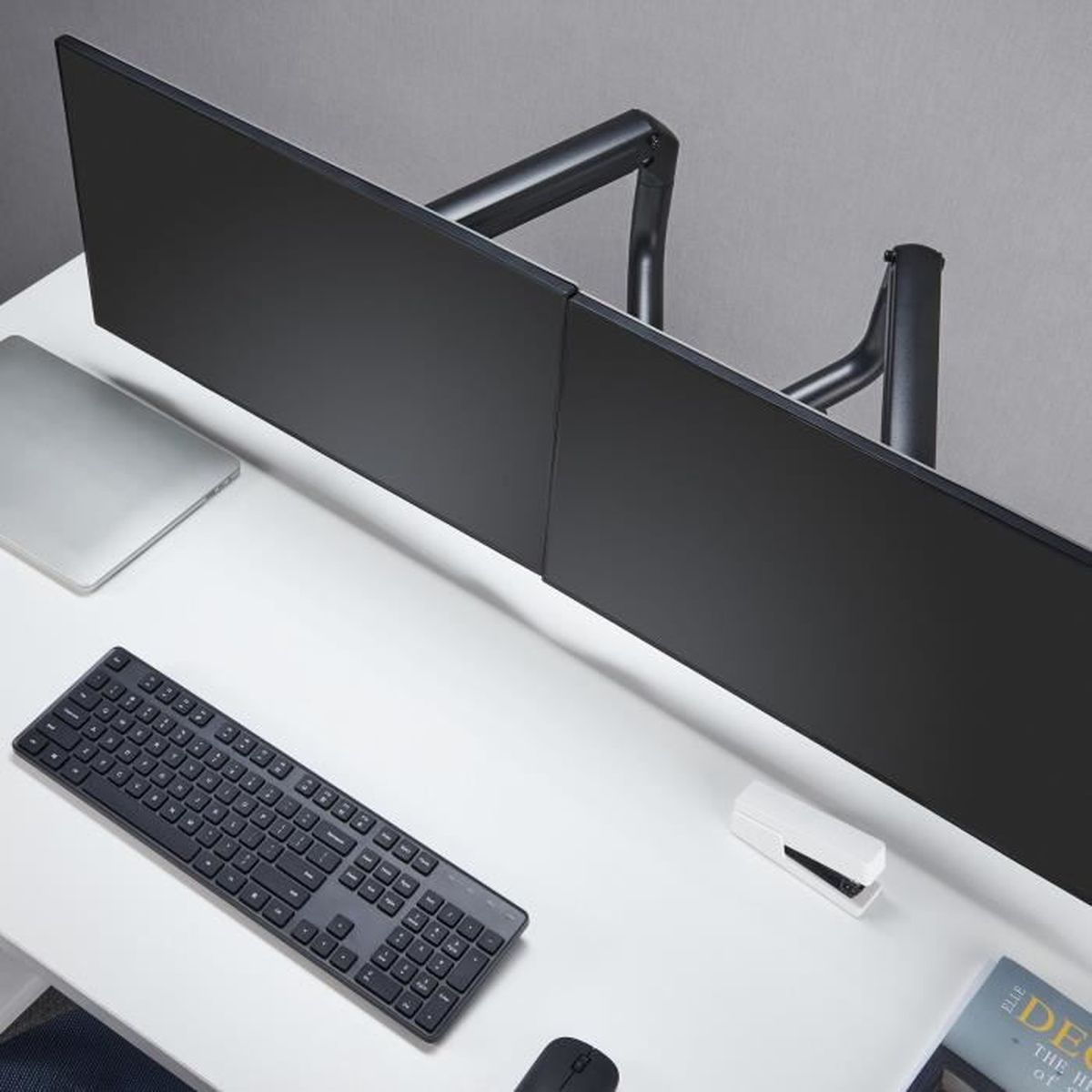 Una scrivania con due monitor neri, una tastiera, un mouse e un laptop.