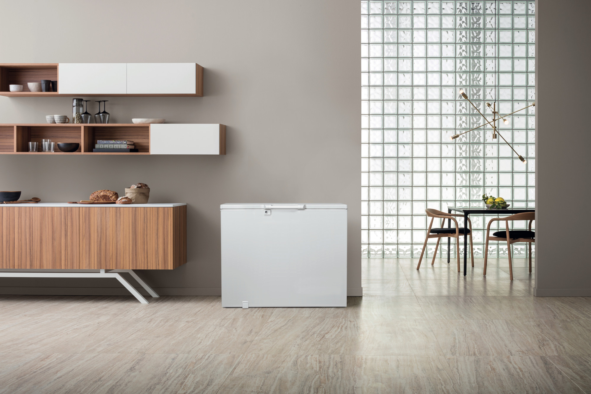 Ein weißer Truhengefrierschrank steht auf einem hellen Fliesenboden neben einem Holzschrank.