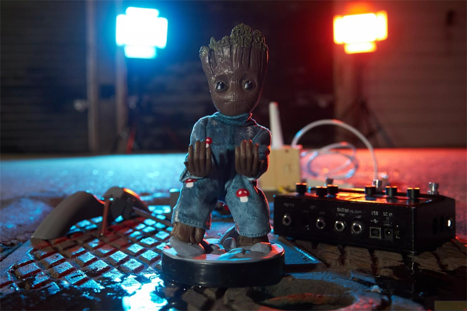 Baby Groot in vestiti blu sta su una grata con luci.