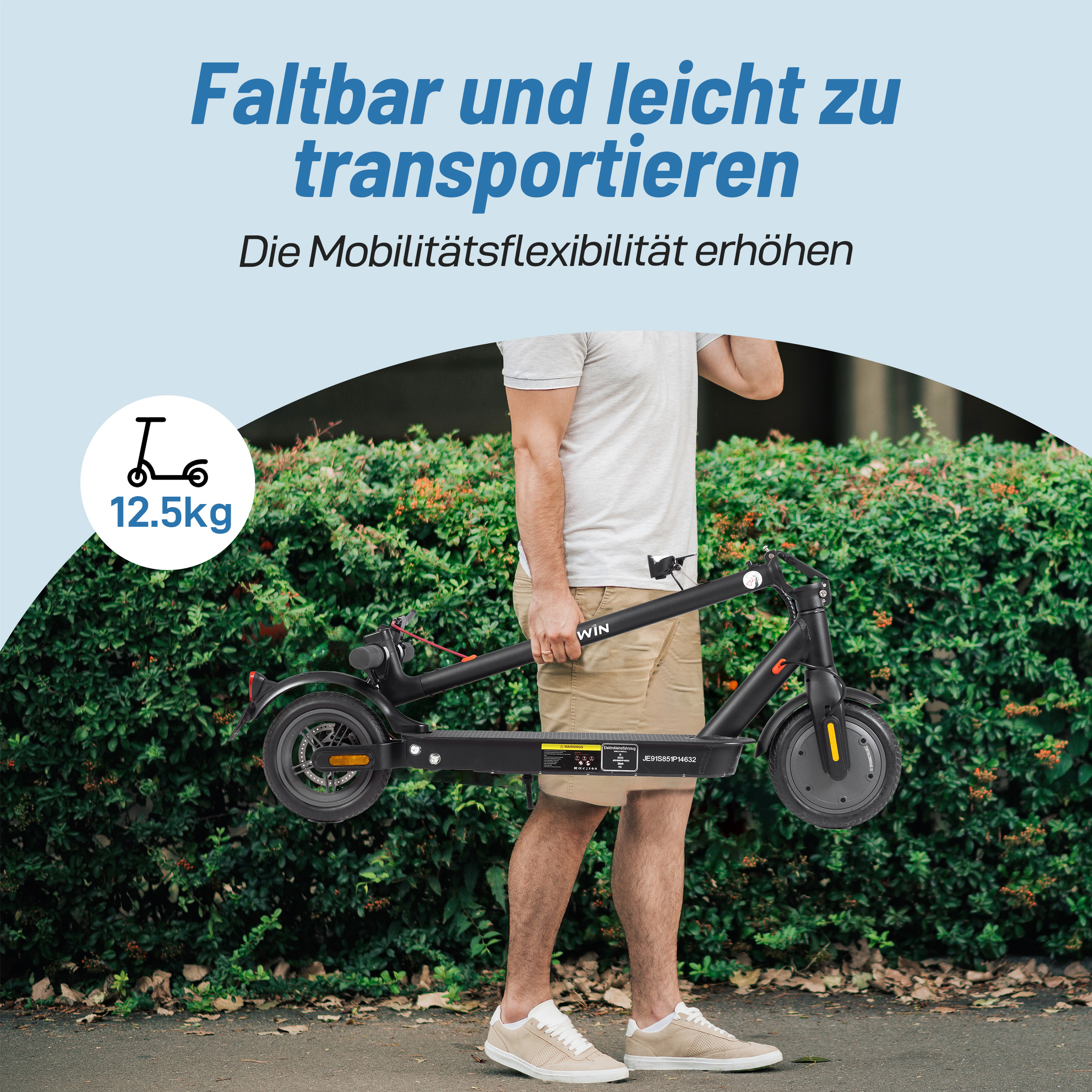 Mann trägt einen schwarzen E-Scooter, 12,5 kg, vor einem grünen Busch.