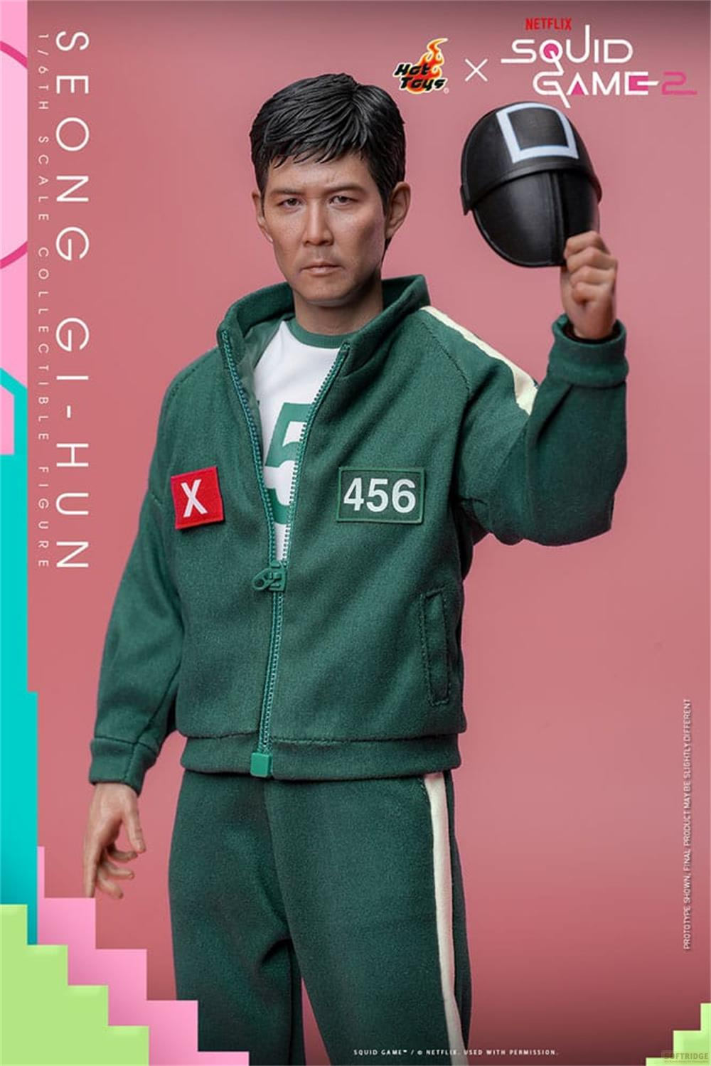 SQUID GAME-Figur, grüne Trainingsjacke mit 456, hält Maske.