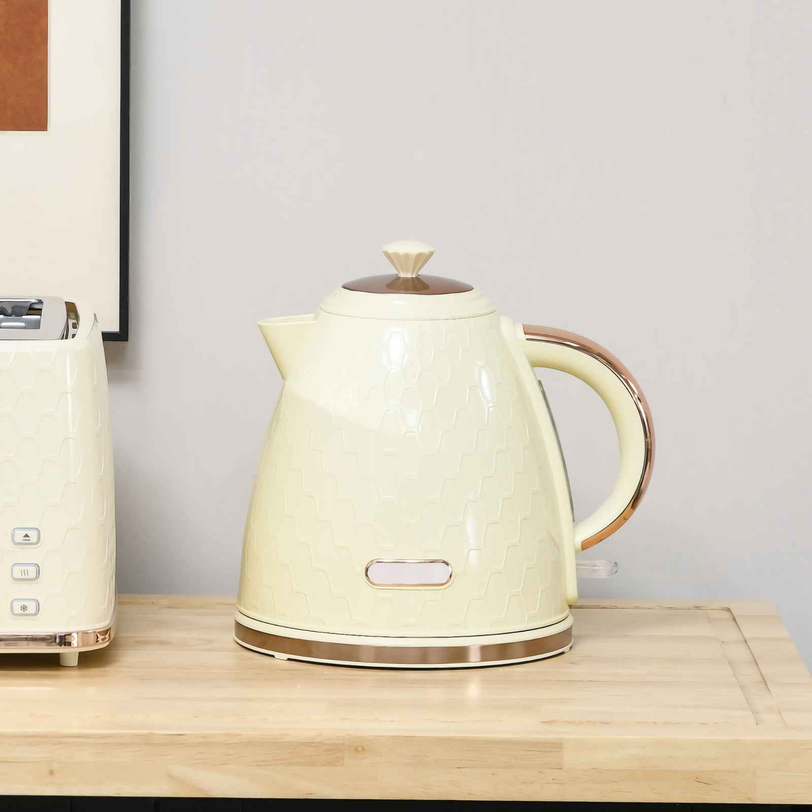 Eine cremefarbene Teekanne mit Wabenmuster und Kupferdetails steht neben einem Toaster.