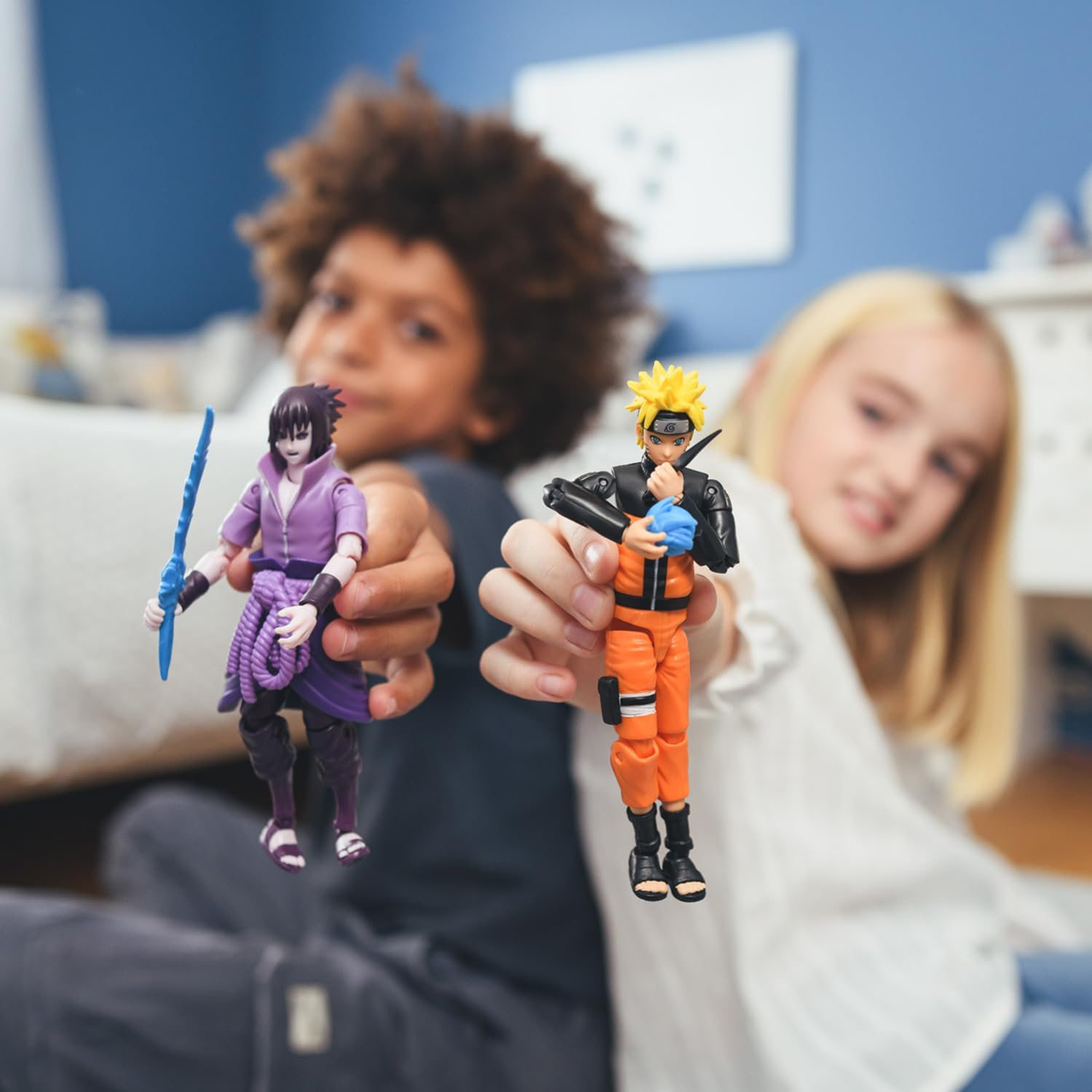 Zwei Kinder halten Naruto- und Sasuke-Actionfiguren. Der Junge hält Sasuke, das Mädchen hält Naruto.