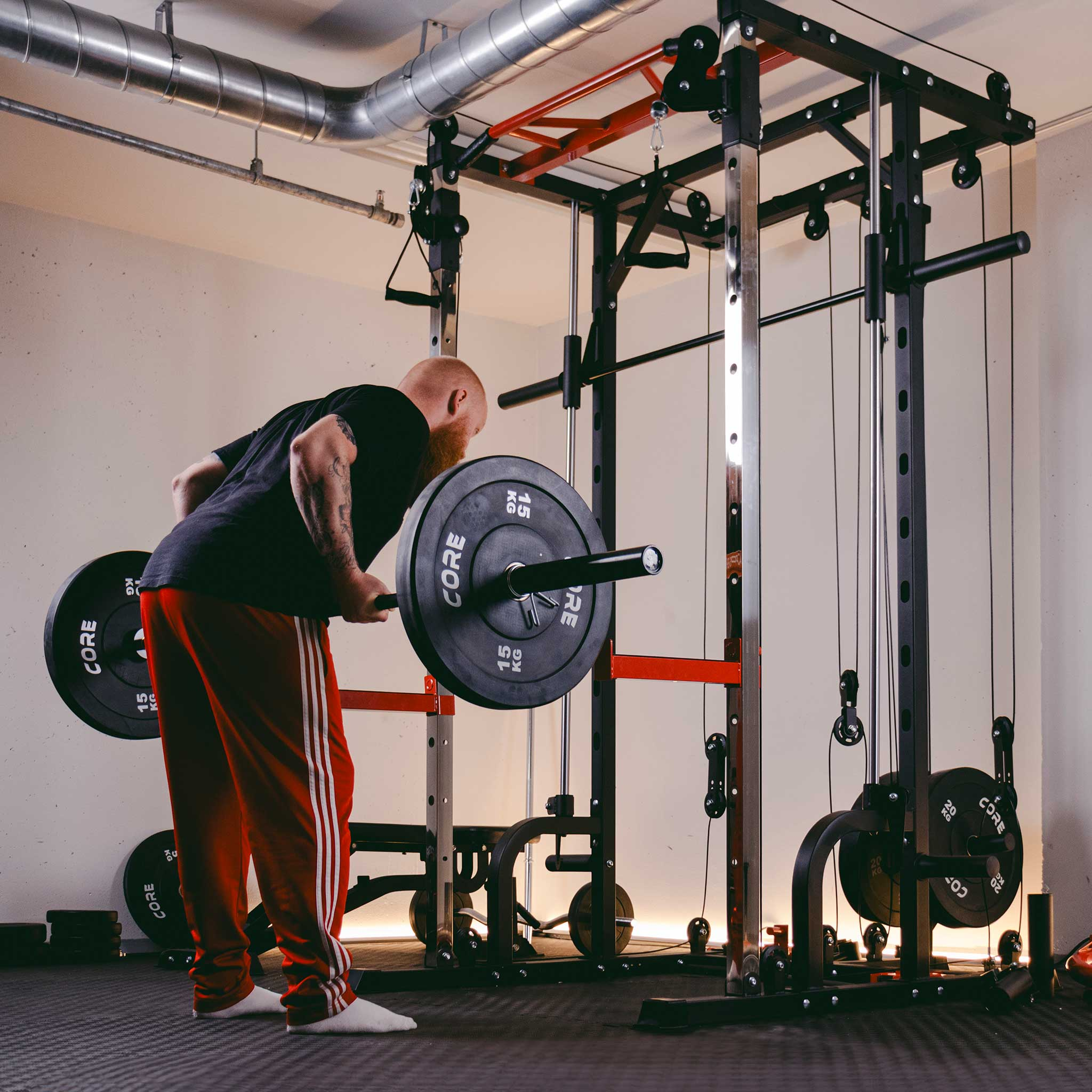 Mężczyzna z brodą trenuje z gryfem w siłowni.