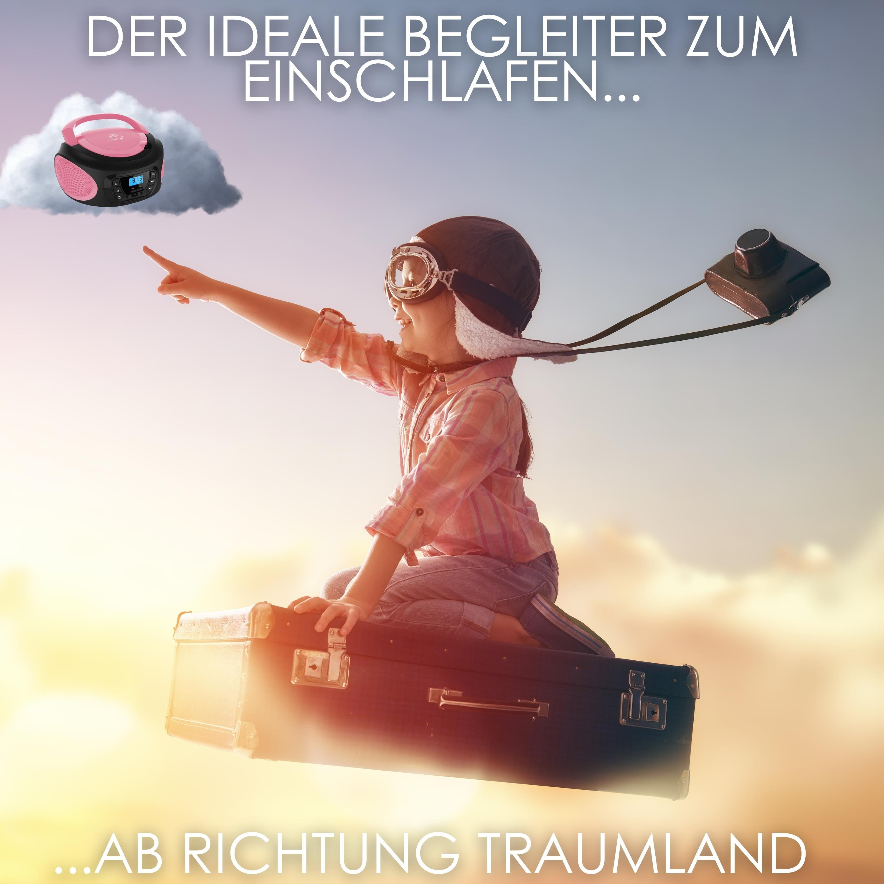 Kind im Pilotenlook sitzt auf Koffer, zeigt in den Himmel.