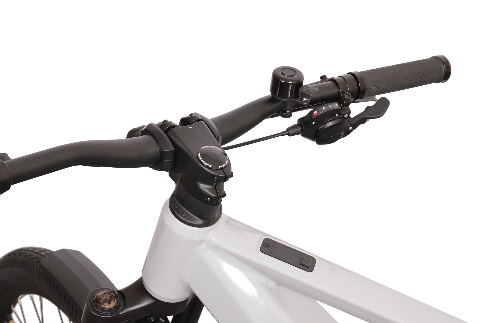 Zbliżenie kierownicy białego roweru z manetką, dzwonkiem i uchwytem.