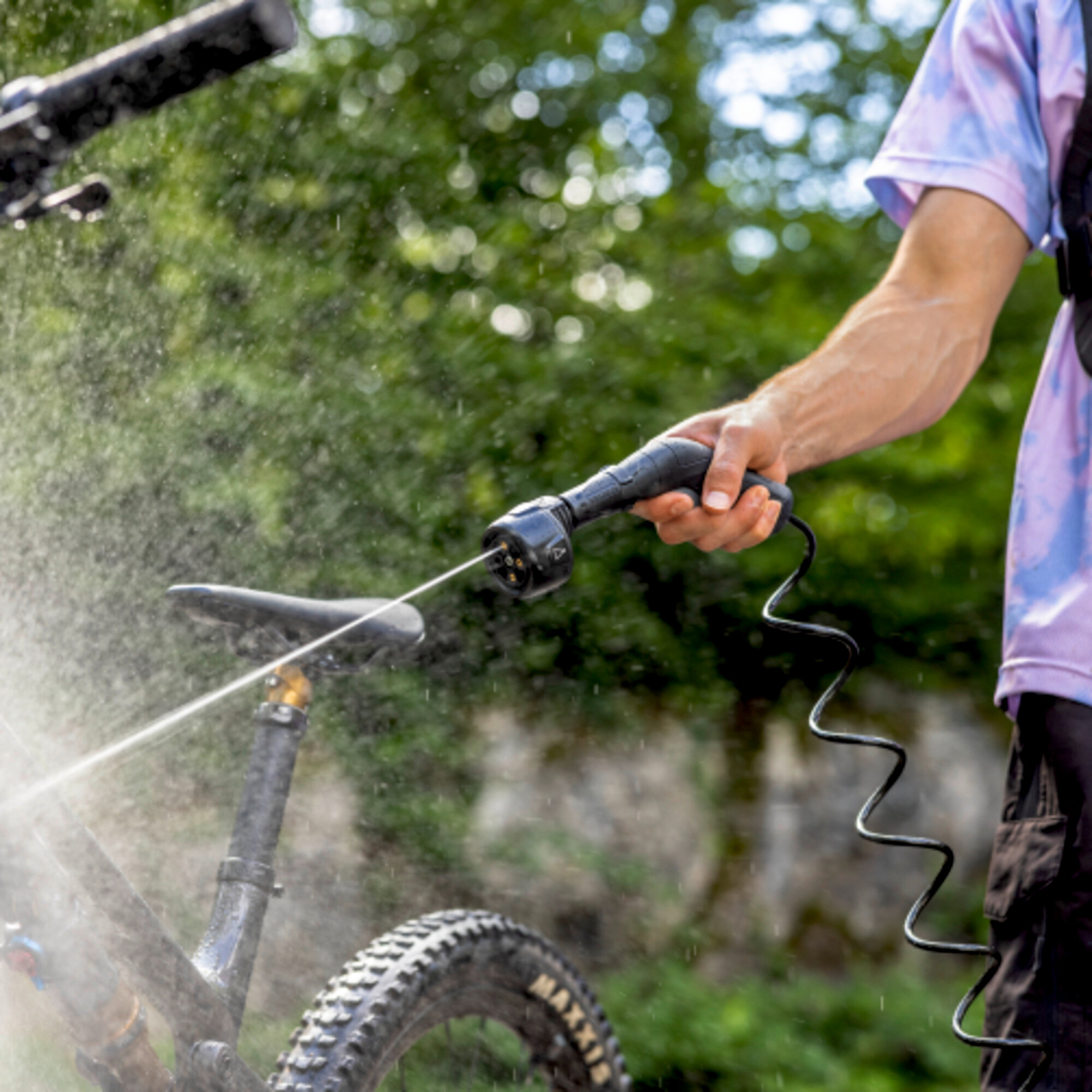 Eine Hand hält eine Spritzpistole, die einen Mountainbike-Rahmen besprüht.
