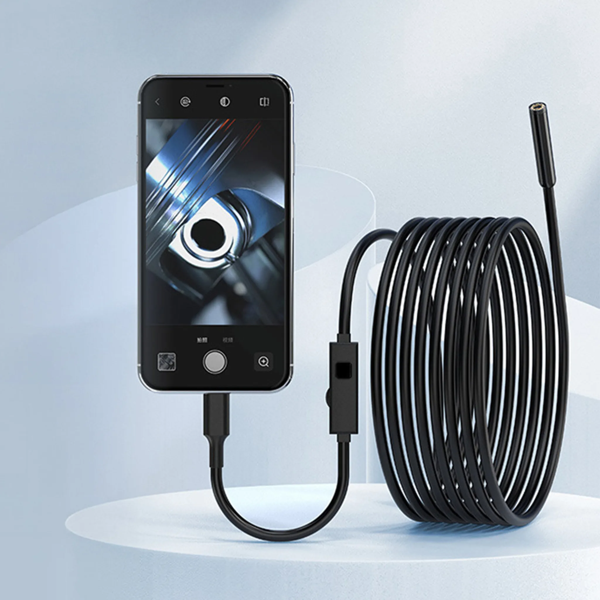 Ein Smartphone zeigt eine Nahaufnahme eines Motors. Ein schwarzes Kabel mit Kamera ist angeschlossen.